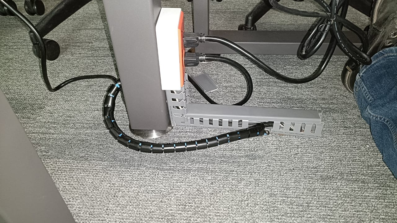Cables agrupados con una funda y una canaleta junto a un escritorio