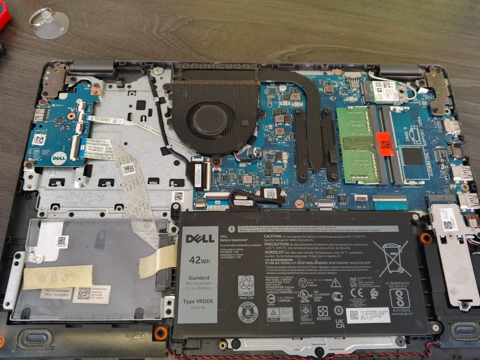 Laptop abierta con batería, ventilador y componentes internos visibles